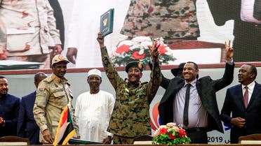 Sudan's protest leader Ahmad Rabie (2nd-R), flashes the victory gesture alongside General Abdel Fattah al-Burhan (C), the chief of Sudan's ruling Transitional Military Council (TMC), during a ceremony where they signed a "constitutional declaration" that paves the way for a transition to civilian rule, in the capital Khartoum on August 17, 2019. (AFP)