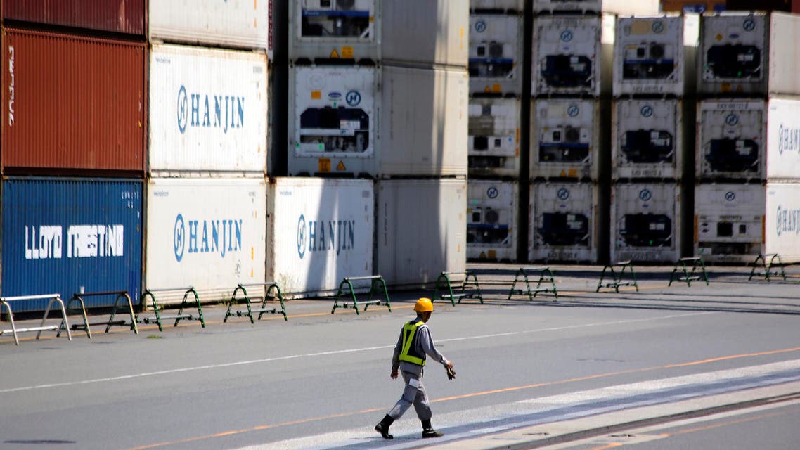 In this Aug. 20, 2014 file photo, a port worker walks past a piles of cargo at a container terminal in Tokyo. (AP)