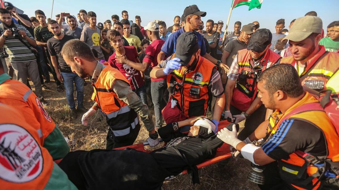 Palestinian paramedics carry a wounded protester during clashes with Israeli forces near the fence along the border with Israel in the eastern Gaza Strip on August 16, 2019. (AFP)
