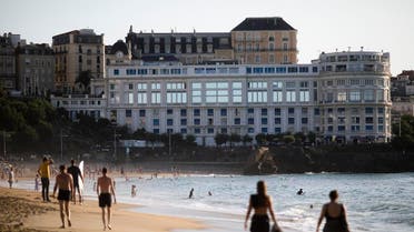 People walk at the beach in front of the G7 summit venue Le Bellevue, on August 21, 2019, in Biarritz, southwestern France. (AP)