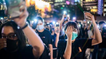 Secondary school students cover their right eye as they hold up their phone torches while attending a rally at Edinburgh Place in Hong Kong on August 22, 2019. (AFP)