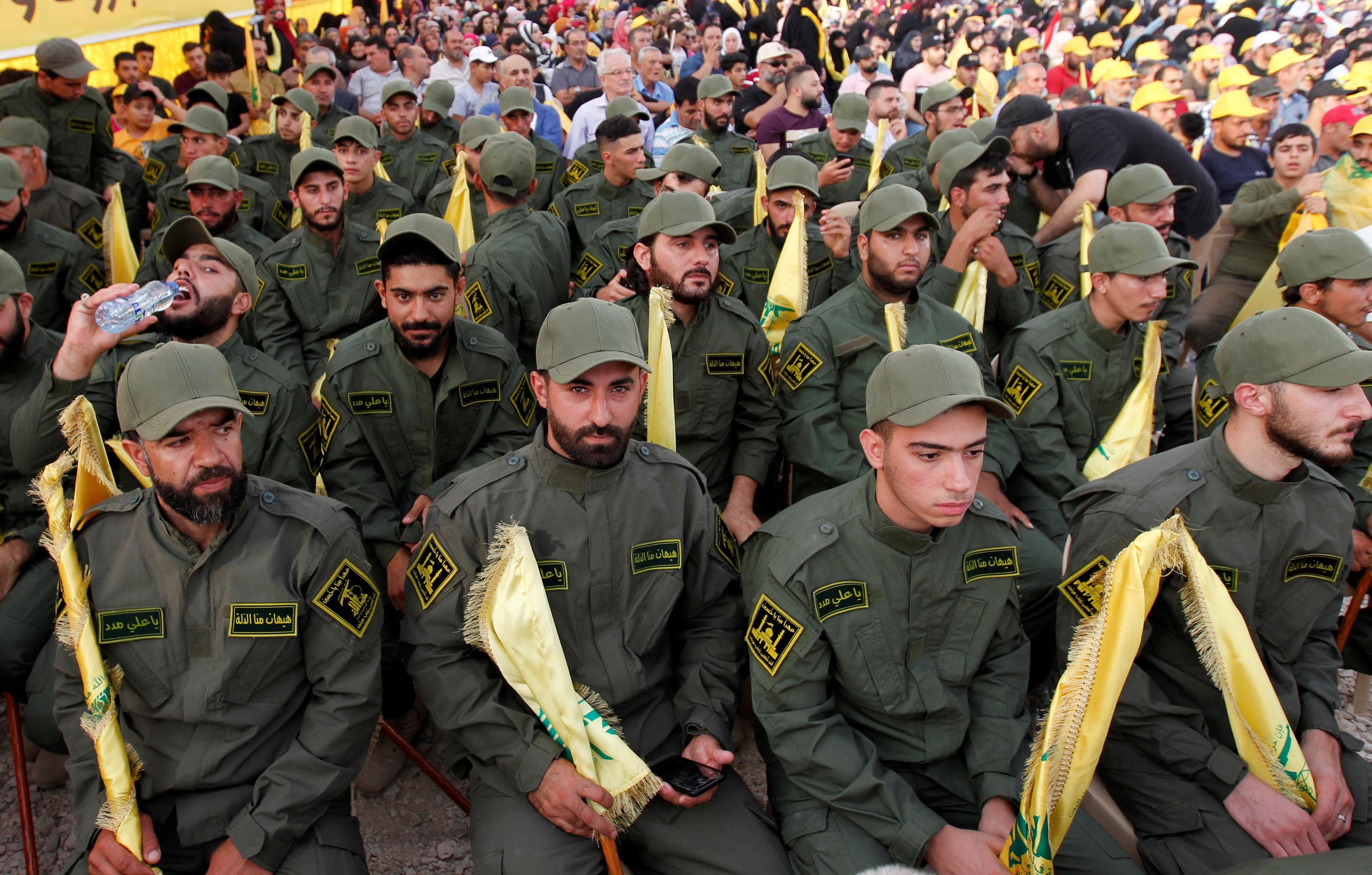 Lebanon's Hezbollah members hold party flags as they listen to their leader Hassan Nasrallah, Aug. 25, 2019. (Reuters)