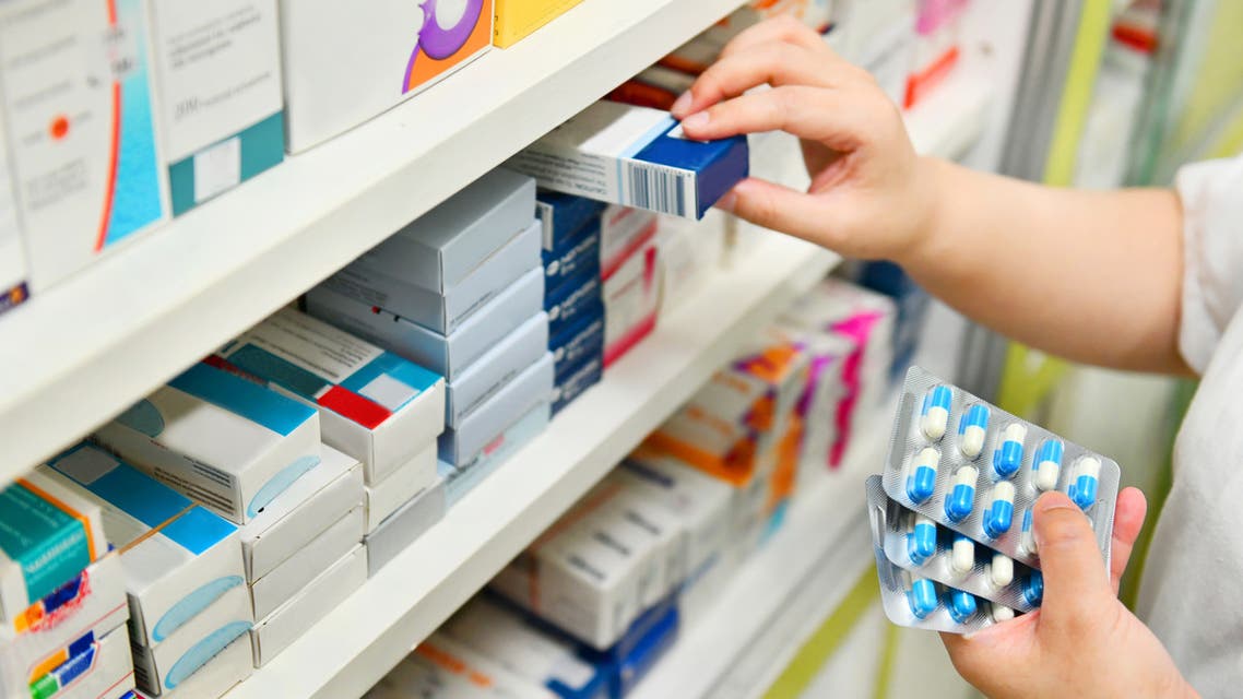 Pharmacist holding medicine box and capsule pack stock photo