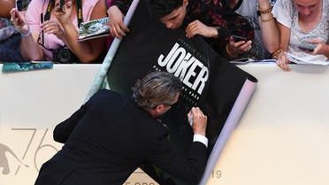 US actor Joaquin Phoenix signs the movie's poster for a fan as he arrives for the screening of the film "Joker" on August 31, 2019 presented in competition during the 76th Venice Film Festival at Venice Lido. (AFP)