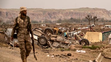A member of the Syrian Democratic Forces (SDF) walks past damaged vehicles on the side of a road in the village of Baghouz in Syria's eastern Deir Ezzor province near the Iraqi border on March 24, 2019, a day after the Islamic State (IS) group's caliphate was declared defeated by the US-backed Kurdish-led Syrian Democratic Forces (SDF). 