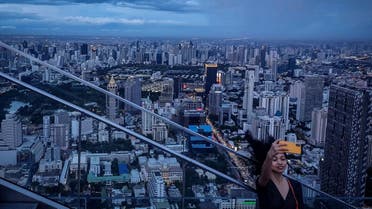 This picture taken on June 26, 2019 shows a tourist taking a selfie photograph in front of the city skyline from the Mahanakorn Skywalk's observation deck area, located 314 metres above the ground, in Bangkok. (AFP)