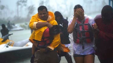 A family is escorted to a safe zone after they were rescued as Hurricane Dorian continues to rain in Freeport, Bahamas. (AP)