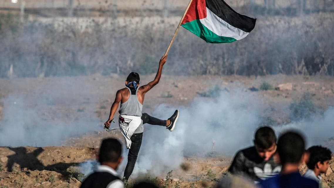 A protester raises a Palestinian flag during clashes with Israeli forces across the border following a demonstration east of Bureij in the central Gaza Strip on September 6, 2019. (AFP)