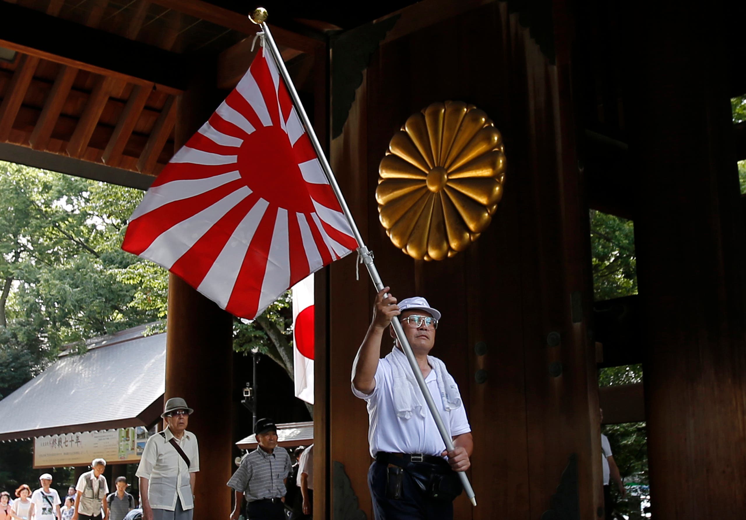 A visitor carries a rising sun flag as they come to the Yasukuni Shrine to pay respects to the country's war dead, in Tokyo, Saturday, Aug. 15, 2015. Japan marked Saturday the 70th anniversary of the end of World War II. (File photo: AP)