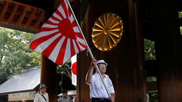A visitor carries a rising sun flag as they come to the Yasukuni Shrine to pay respects to the country's war dead, in Tokyo, Saturday, Aug. 15, 2015. Japan marked Saturday the 70th anniversary of the end of World War II. (AP Photo/Shuji Kajiyama)
