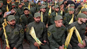 Hezbollah members hold party flags as they listen to their leader Hassan Nasrallah addressing his supporters. (File photo: Reuters)