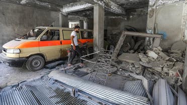 A man walks past a damaged mini-van that was used as a make-shift ambulance amidst debris in the garage of a hospital damaged after a reported air strike in Jisr al-Shughur in the northeastern Syrian Idlib province on July 10, 2019. (AFP)