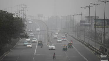 In this Jan. 15, 2016, file photo, an Indian woman crosses a road as vehicles move through morning smog on the last day of a two-week experiment where the Delhi government allowed private cars on the roads on alternate days depending on whether their license plates end in an even or an odd number, to reduce the number of cars to fight pollution in New Delhi, India. (AP)