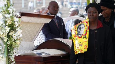A mourner with a regalia bearing the face of Mugabe, walks after paying her last respects to Robert Mugabe's body as it lies in state at the at Rufaro stadium. (Reuters)