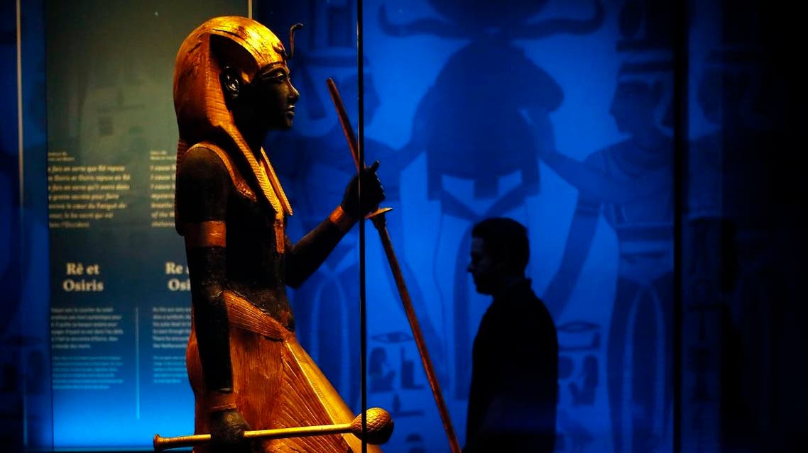 A visitor walks by a wooden guardian statue of the Ka of the king wearing the Names Headcloth displayed as part of 'Tutankhamun, the treasure of the Pharaoh', an exhibition in partnership with the Grand Egyptian Museum at the Grande Halle of La Villette in Paris. (AP)