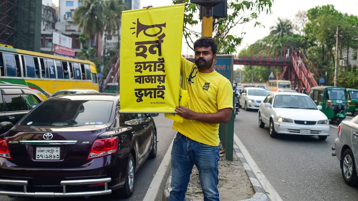 In this photo taken on March 22, 2019, Mominur Rahman Royal holds a banner with a Bengali slogan -- Horn hudai, Bajay Bhudai that translates to only the idiot honks horn unnecessarily -- on a busy street in Dhaka. Bangladeshi Mominur Rahman Royal is stopping traffic -- literally. The 36-year-old is on a one-man crusade to reduce unnecessary honking in one of the world's noisiest cities, where the cacophony of vehicle horns in heavy traffic is as loud as a rock concert.