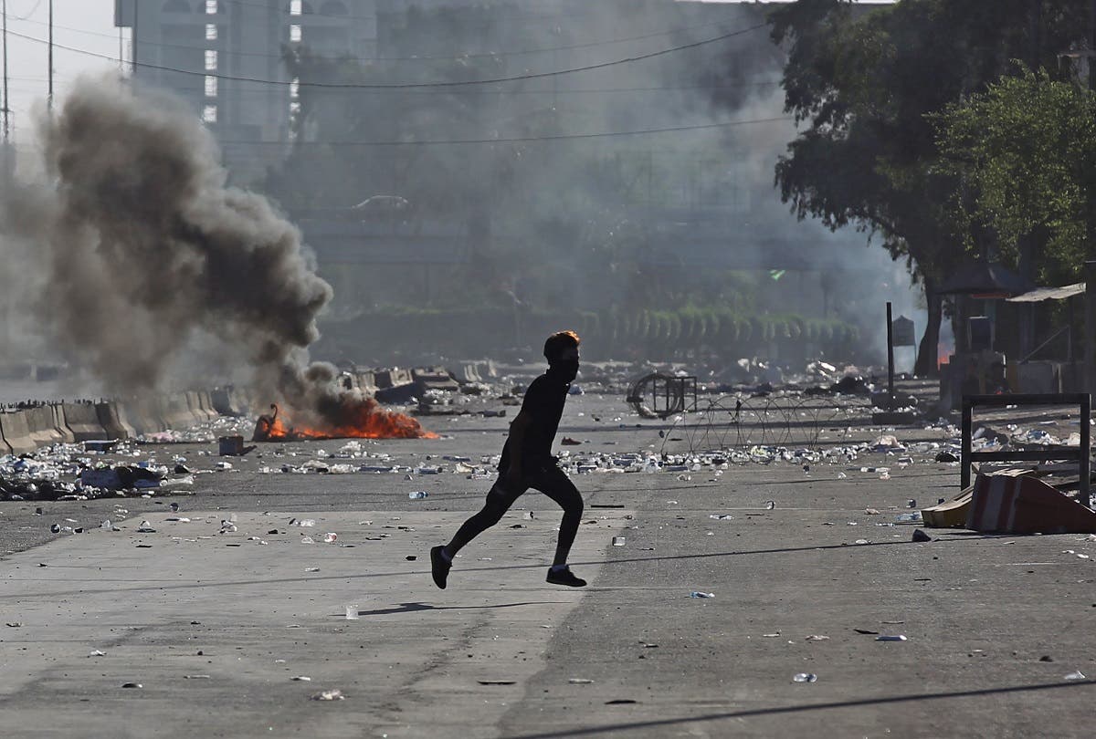 An Iraqi protester runs amidst clashes during a demonstration against state corruption, failing public services, and unemployment in the Iraqi capital Baghdad's central Khellani Square on October 4, 2019. (AFP)