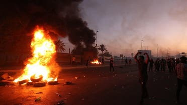 An Iraqi demonstrator gestures next to a tyre fire during a demonstration against state corruption, failing public services, and unemployment, in the Iraqi capital Baghdad on October 5, 2019. (AFP)