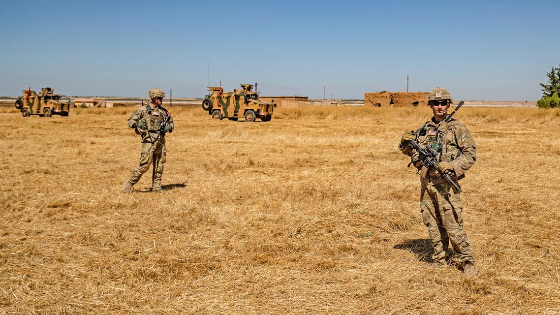 US soldiers stand close to Turkish military vehicles during a joint patrol with Turkey in the Syrian village of al-Hashisha on the outskirts of Tal Abyad town along the border with Turkey September 2019 REUTERS