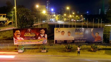 A Sri Lankan man stands near billboards displaying President Maithripala Sirisena, right, and former president Mahinda Rajapaksa, left, in Colombo, Sri Lanka, Wednesday, Sept. 18, 2019. (AP)