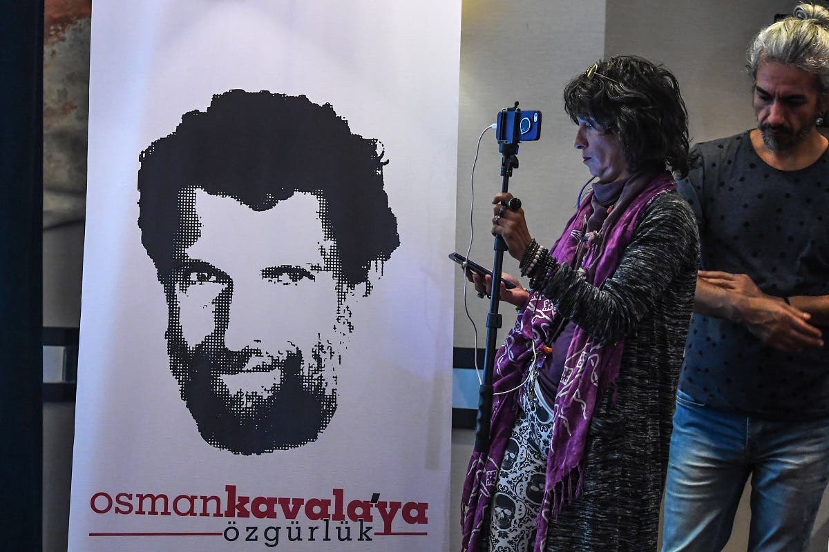 A journalist stands in front of a poster featuring jailed businessman and philanthropist Osman Kavala during a press conference of his lawyers on October 31, 2018. (AFP)