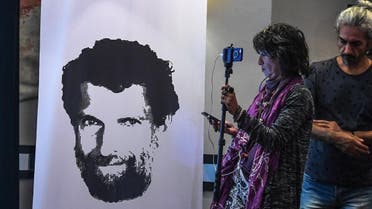 A journalist stands in front of a poster featuring jailed businessman and philanthropist Osman Kavala during a press conference of his lawyers on October 31, 2018. (AFP)