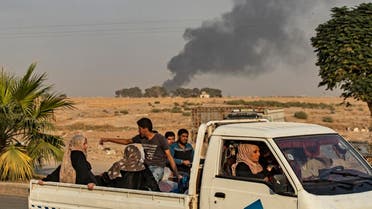 Civilians ride a pickup truck as smoke billows following Turkish bombardment on Syria's northeastern town of Ras al-Ain in the Hasakeh province along the Turkish border on October 9, 2019. (AFP)
