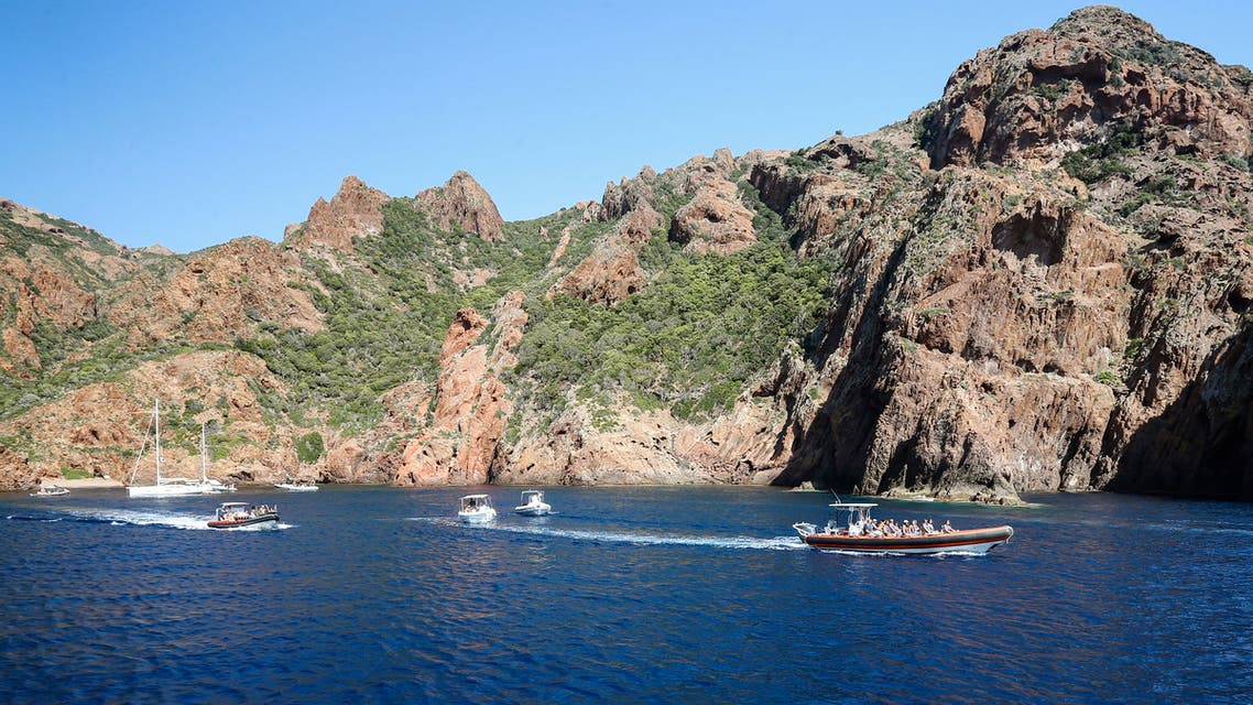 Tourists take a cruise on August 19, 2019, in the Scandola Nature Reserve, on the western coast of the French Mediterranean island of Corsica. The Scandola Nature Reserve park, created in 1975, is an ecological dream, being a nature reserve and a protected marine zone that is listed by France's coastal protection agency and Natura 2000, in addition to its recognition by UNESCO. It is a prime destination for the some three million people who visit Corsica each year, 75 percent of them in the summer. The paradox is that growing numbers of tourists are drawn to Scandola's pristine waters and stunning geological vistas, endangering its fragile ecosystem.