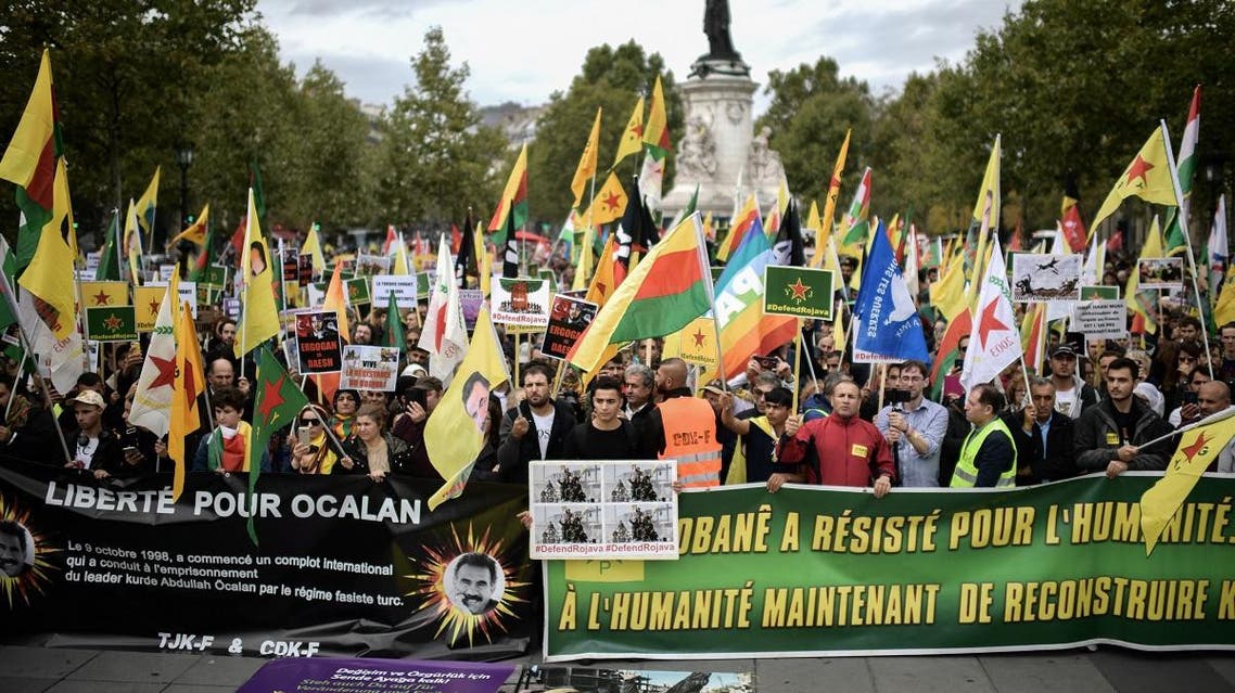People hold pro-Kurd flags and banner in Paris on October 12, 2019 during a demonstration to support Kurdish militants and protest as Turkey kept up its assault on Kurdish-held border towns in northeastern Syria. (AFP)