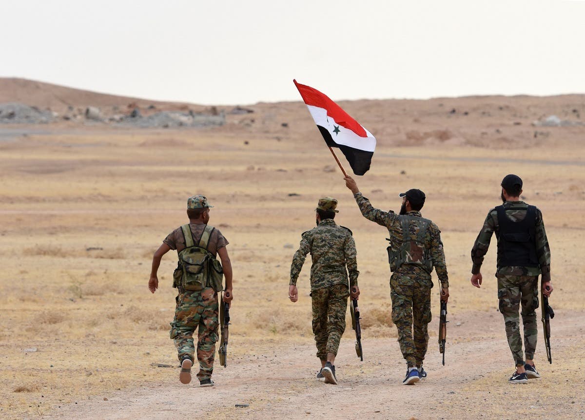 Syrian government forces raise their national flag at Tabqa air base in norther Syria’s Raqa region on October 16, 2019. (AFP)