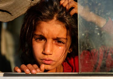 A Syrian girl who is newly displaced by the Turkish military operation in northeastern Syria, weeps as she sits in a bus upon her arrival at the Bardarash camp, north of Mosul, Iraq. (AP)