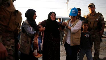 UNHCR members helps a Syrian woman who is newly displaced by the Turkish military operation in northeastern Syria, upon her arrival at the Bardarash camp, north of Mosul, Iraq. (AP)