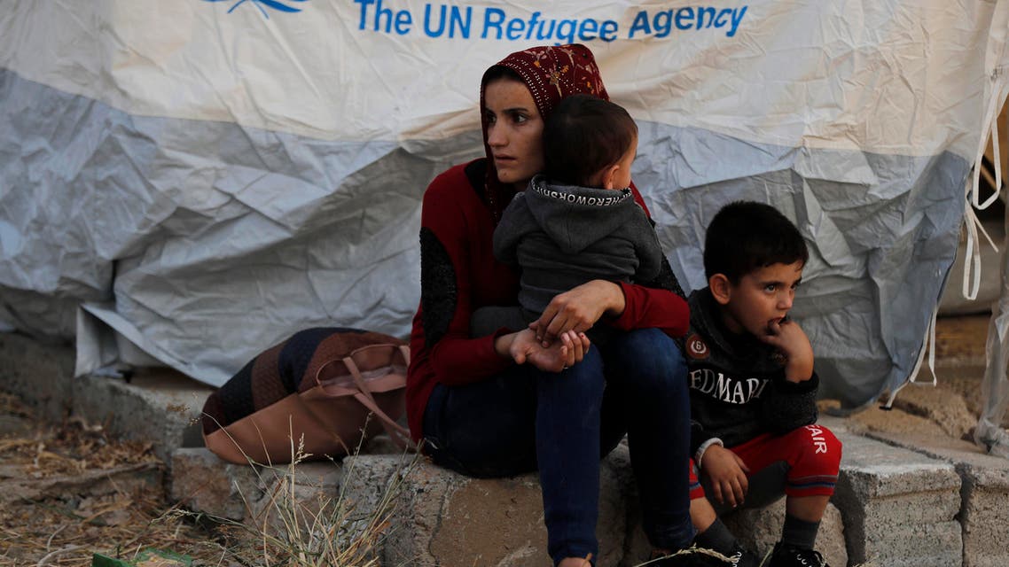 A Syrian woman with her children, who were displaced by the Turkish military operation in northeastern Syria, wait to receive a tent and other aid supplies at the Bardarash refugee camp, north of Mosul, Iraq, Thursday, Oct. 17, 2019. (AFP)