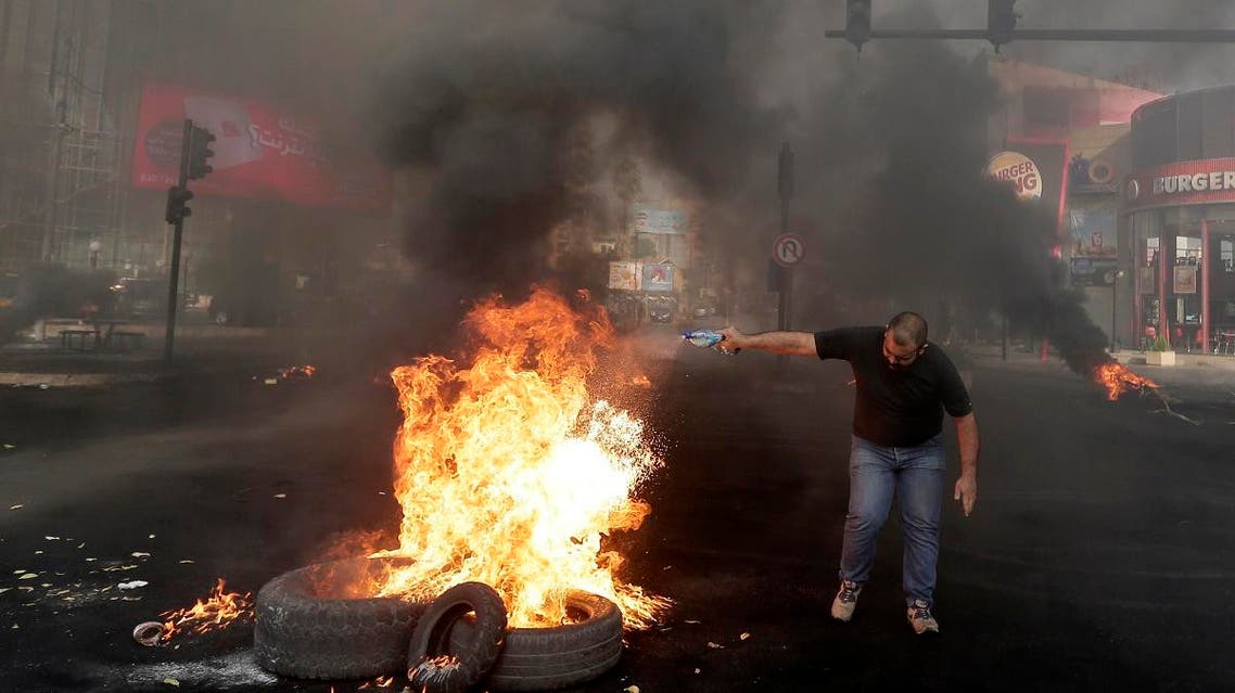An anti-government protester sets fire on tires to block a road during a protest against government's plans to impose new taxes in Beirut, Lebanon, Friday, Oct. 18, 2019. (AP)