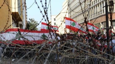 Lebanese demonstrators wave the national flag on barbed wire protecting the government headquarters, known as the Grand Serail in central Beirut, as hundreds continued to gather in Lebanon on October 19, 2019 for a third day of protests. (AFP)