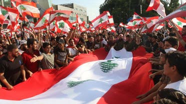 Lebanese demonstrators wave national flags as they take part in a protest against dire economic conditions in Lebanon's southern city of Sidon on October 20, 2019. (AFP)