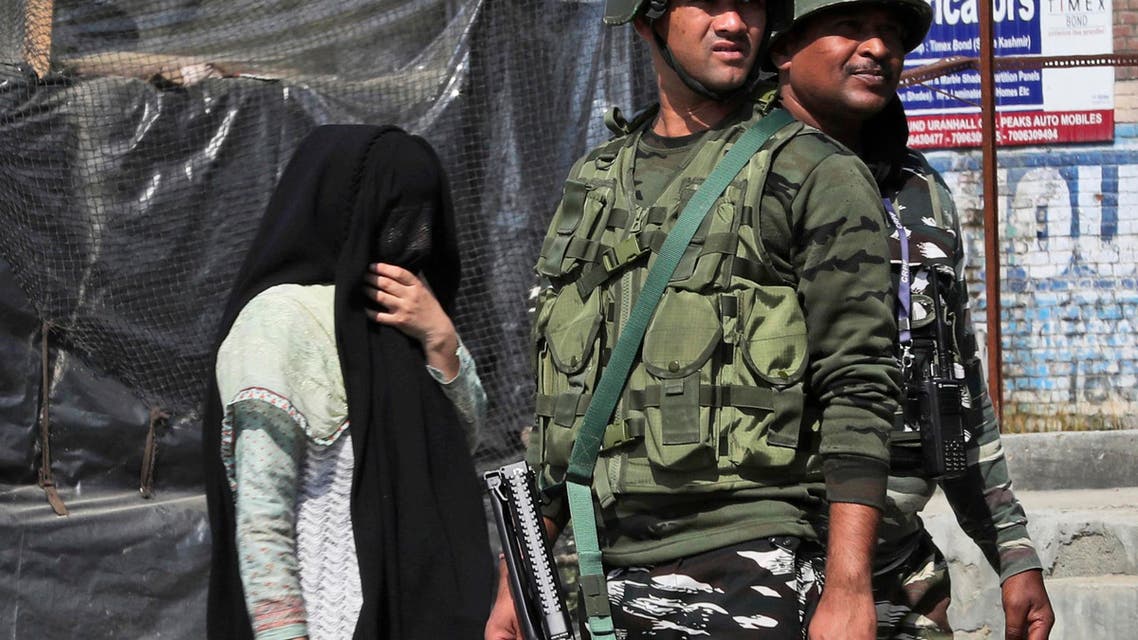 A Kashmiri woman walks past paramilitary soldiers standing guard near the site of a gunbattle in Bijbehara, south of Srinagar, Indian controlled Kashmir, Wednesday, Oct. 16, 2019. (AP)