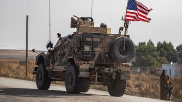 A Syrian woman and a child stand on the side of a road as a US military vehicle drives on a road after US forces pulled out of their base in the Northern Syriain town of Tal Tamr, on October 20, 2019. (AFP)