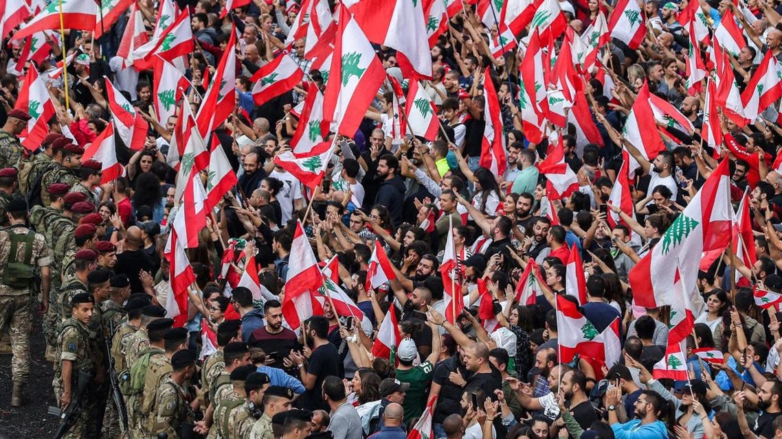 Protesters stand with Lebanese national flags before Lebanese army soldiers along the side of the Beirut-Jounieh highway in the northern Beirut suburb of Jal el-Dib amidst on the seventh day of protest against tax increases and official corruption, on October 23, 2019. (AFP)