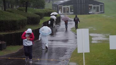 Spectators walk in the rain as the PGA ZOZO Championship golf tournament had been postphoned at the Narashino Country Club in Inzai, Chiba. (AFP)