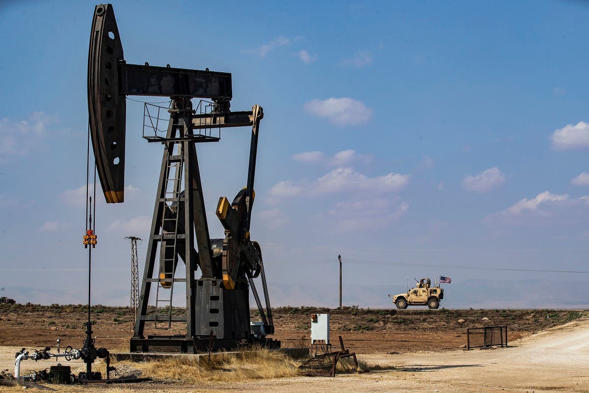 A US military vehicle, part of a convoy arriving from northern Iraq, drives past an oil pump jack in the countryside of Syria’s northeastern city of Qamishli on October 26, 2019. (AFP)