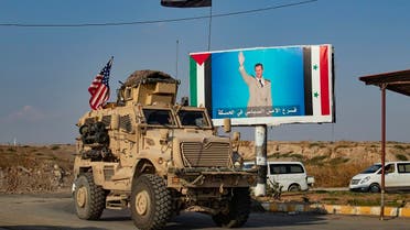 A US military vehicle drives near a checkpoint controlled by the Syrian government forces in Syria’s northeastern city of Qamishli on October 26, 2019. (AFP)