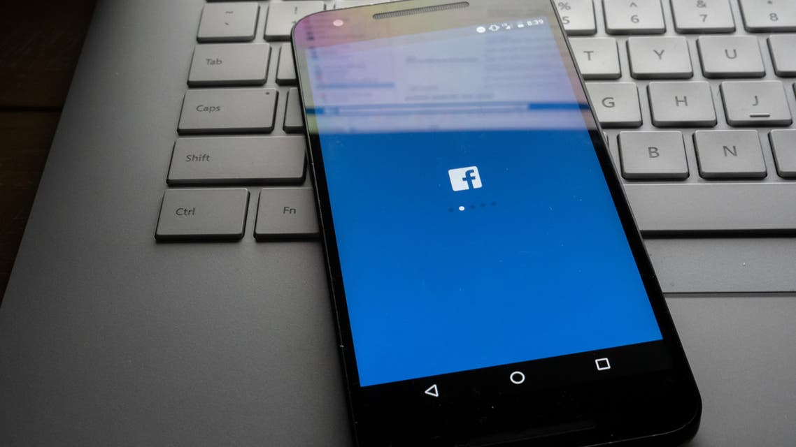 Phone sitting on laptop with Facebook desktop site sitting on screen. stock photo