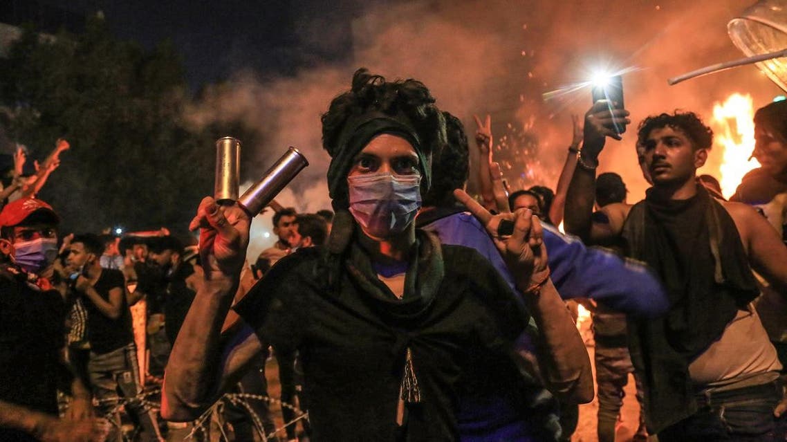 A protester wears tear gas canisters on his fingers and gestures the victory sign during anti-government protests in the Shiite shrine city of Karbala, south of Iraq's capital Baghdad, late on October 28, 2019. (AFP)