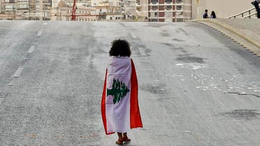 A Lebanese woman protester walks draped in a national flag along the Fuad Chehab avenue, near the Martyrs' Square, in the centre of the capital Beirut. (AFP)