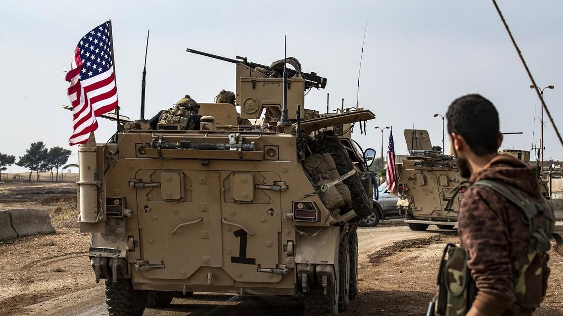 A fighter with the Syrian Democratic Forces (SDF) stands on the side of a road as a convoy of US troops drives by outside the Kurdish-majority city of Qamishli, in Syria’s northeastern Hasakeh province on November 2, 2019. (AFP)