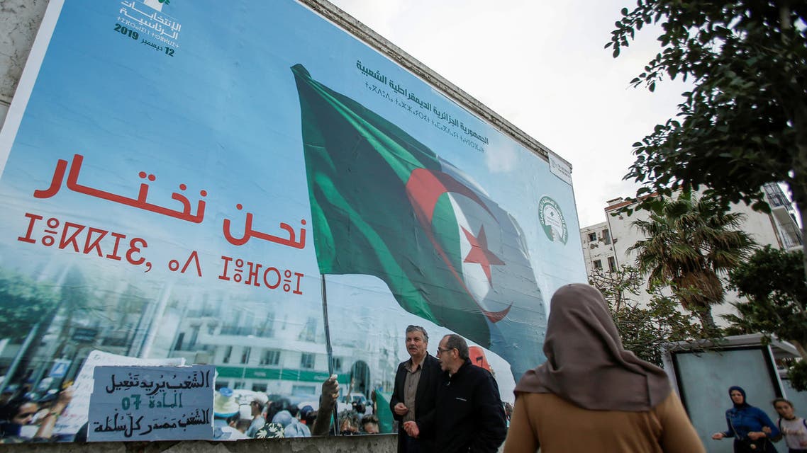 People walk past a campaign poster for presidential election in Algiers Algeria November 2 2019 REUTERS