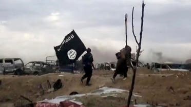This frame grab from video posted online Monday, March 18, 2019, shows ISIS fighters carrying the group’s flag inside Baghouz, Syria. (File photo: AP)