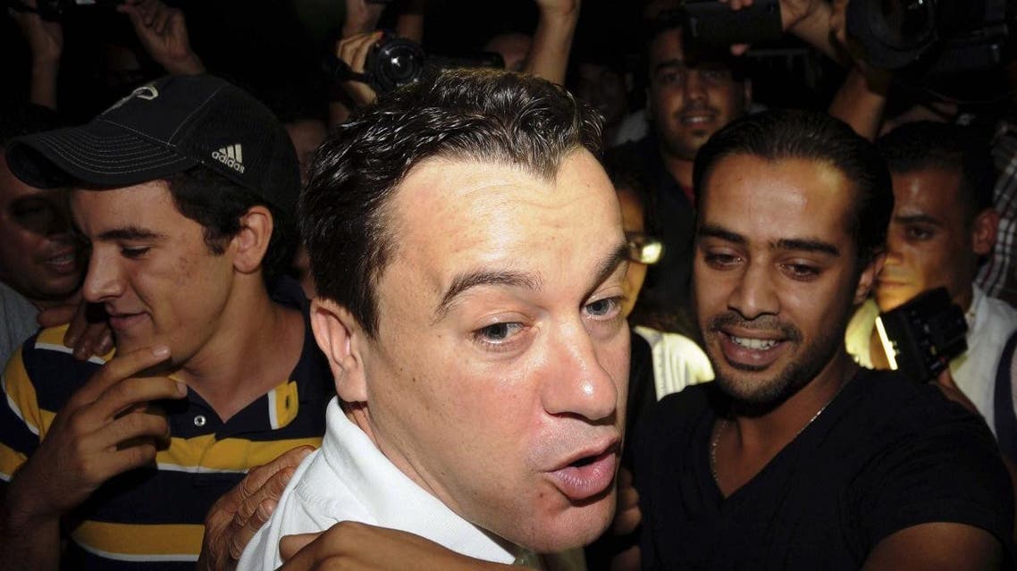 In this photo taken on Wednesday night, Sept. 11, 2013, Sami El Fehri, foreground, the head of a private Tunisian TV channel, reacts with the media, after being released after a year in prison, near Tunis. (AP)