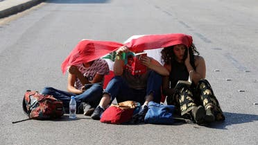 Demonstrators sit on the ground and read along a blocked road in Beirut. (Reuters)